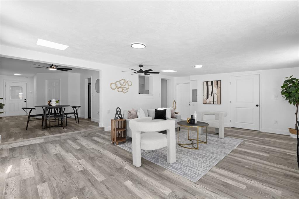 A living room and dining area feature white walls, gray wood-look flooring, and modern furniture — 1259 SCOTTSDALE DRIVE, ORMOND BEACH, FL