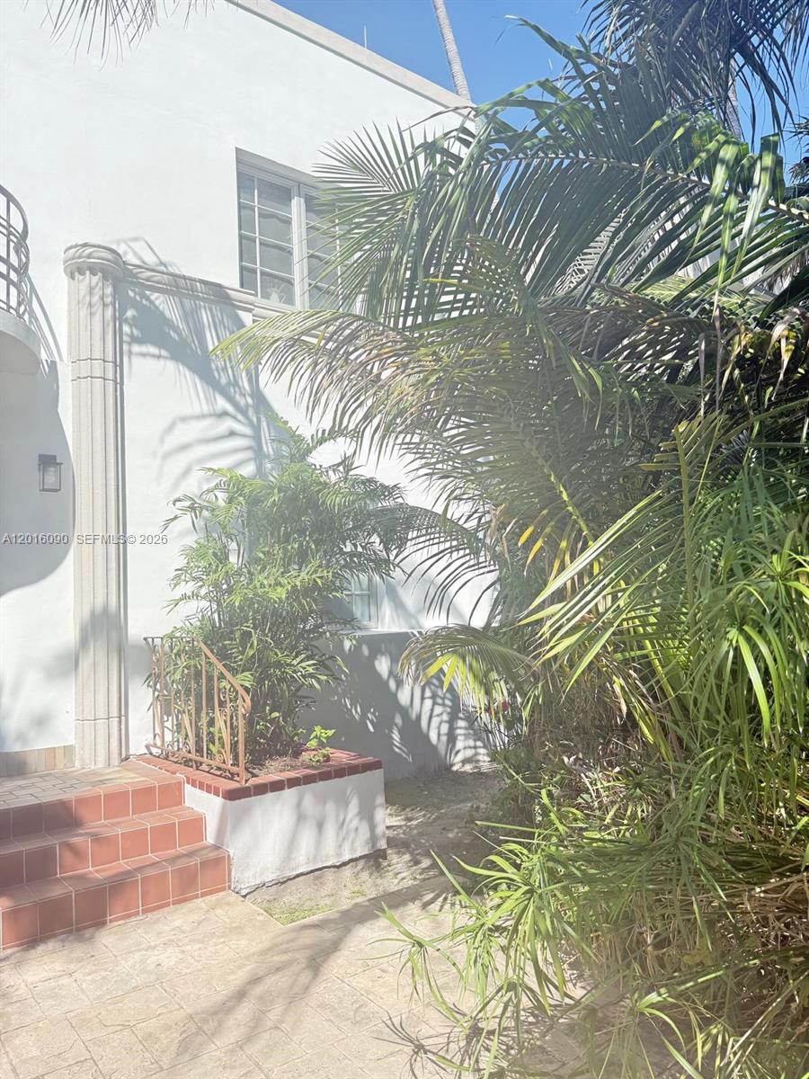 A white building exterior features a tiled staircase, a small planter, and lush palm trees — 920 Euclid Ave # 3, Miami Beach FL 33139, MIAMI BEACH, FL