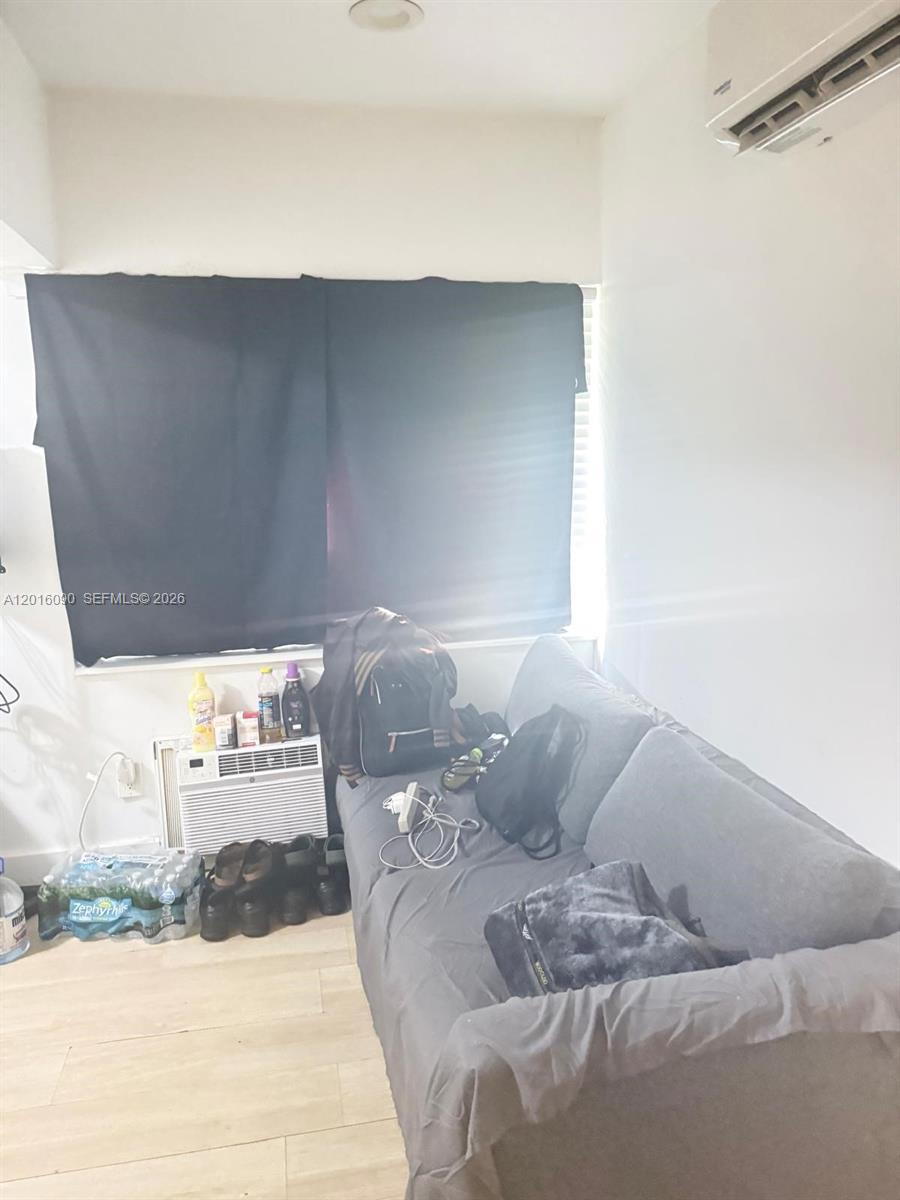 A room features a gray sofa, a window with black curtains, and a wall-mounted air conditioner — 920 Euclid Ave # 3, Miami Beach FL 33139, MIAMI BEACH, FL