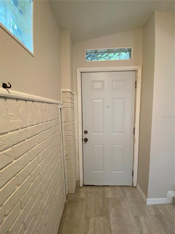An entryway features a white door, a painted brick wall, and light-colored tile flooring — 7222 NIMA COURT, ORLANDO, FL