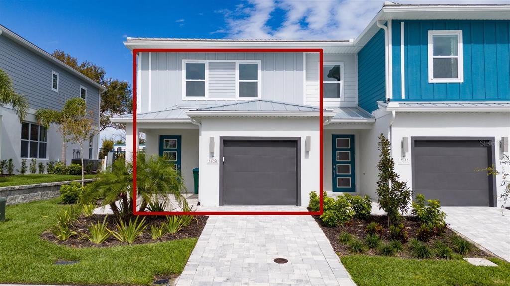 A two-story townhouse exterior features a gray garage, light siding, and a paved driveway — 7845 SPECTRUM DRIVE, KISSIMMEE, FL