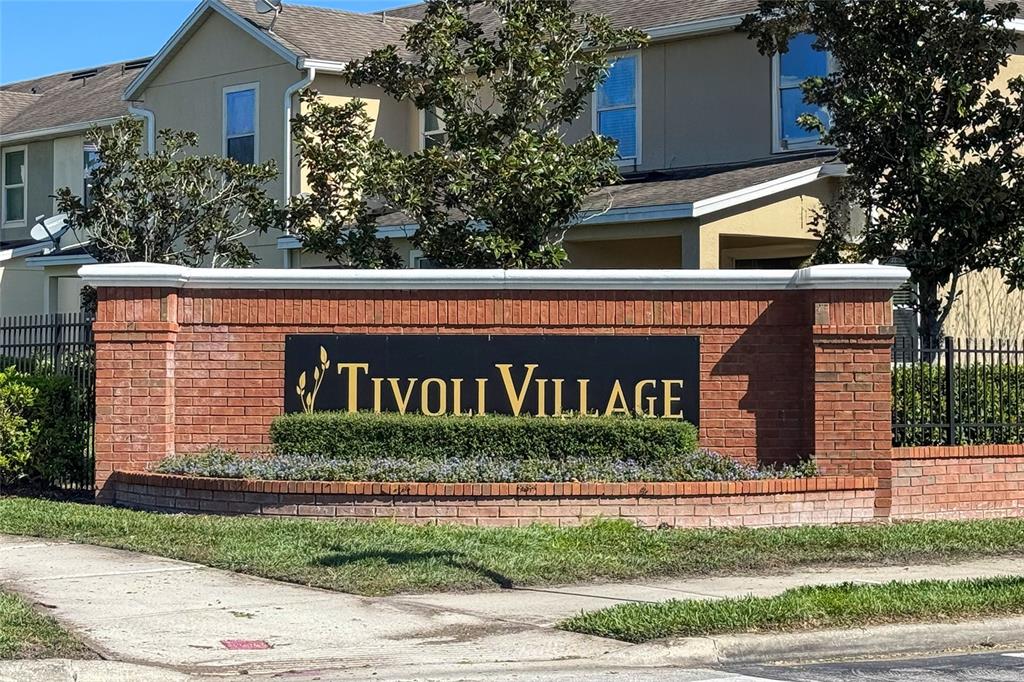 A brick monument sign for Tivoli Village stands in front of a two-story residential building — 5412 CARAMELLA DRIVE, ORLANDO, FL
