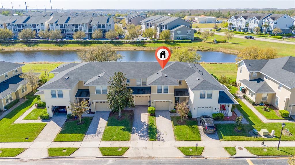 An aerial view shows a row of townhouses with attached garages and a nearby pond — 5412 CARAMELLA DRIVE, ORLANDO, FL