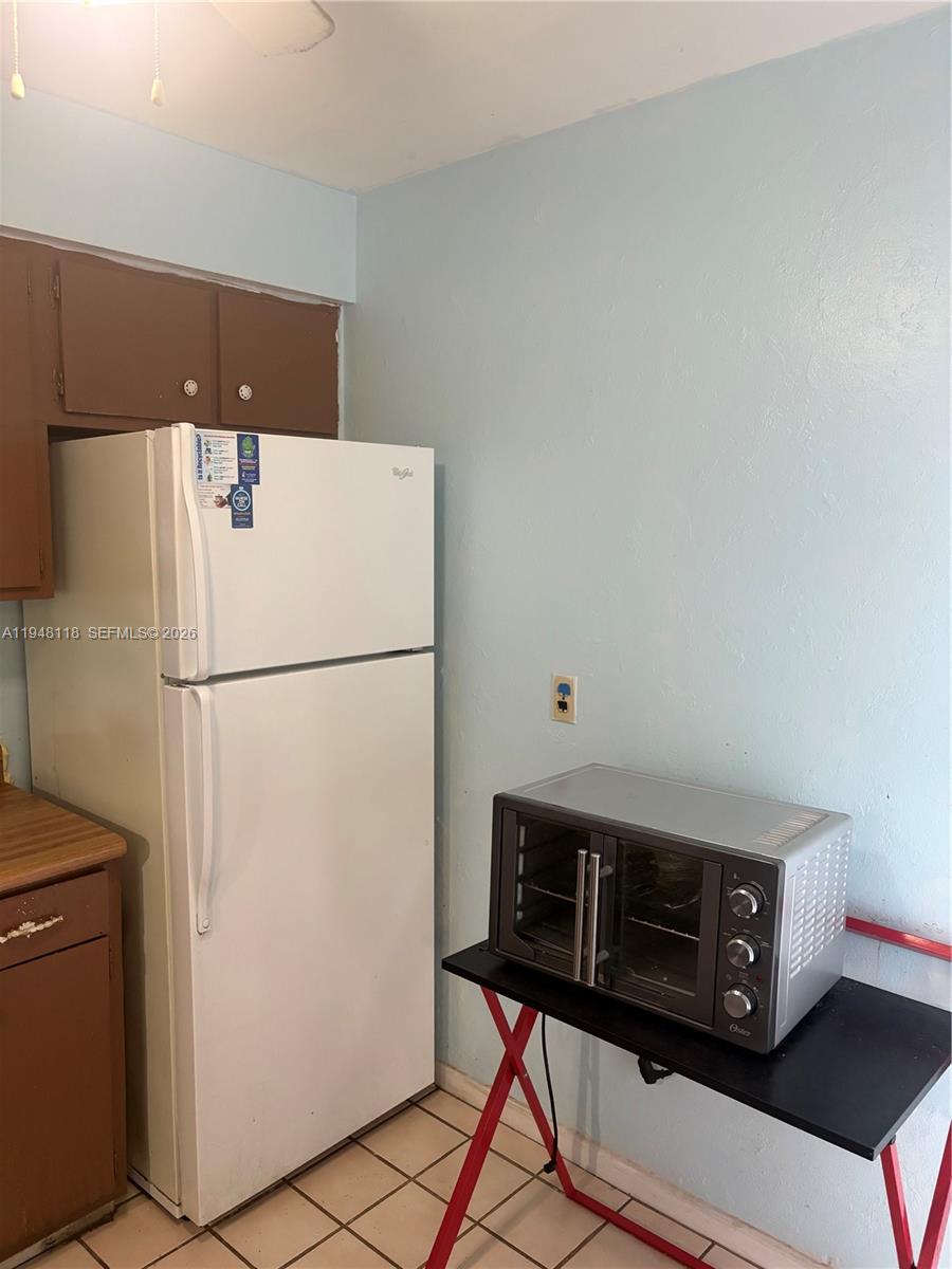 A white refrigerator stands next to a toaster oven on a folding table in a kitchen — 108 Coolidge ave, Lehigh Acres FL 33936, LEHIGH ACRES, FL