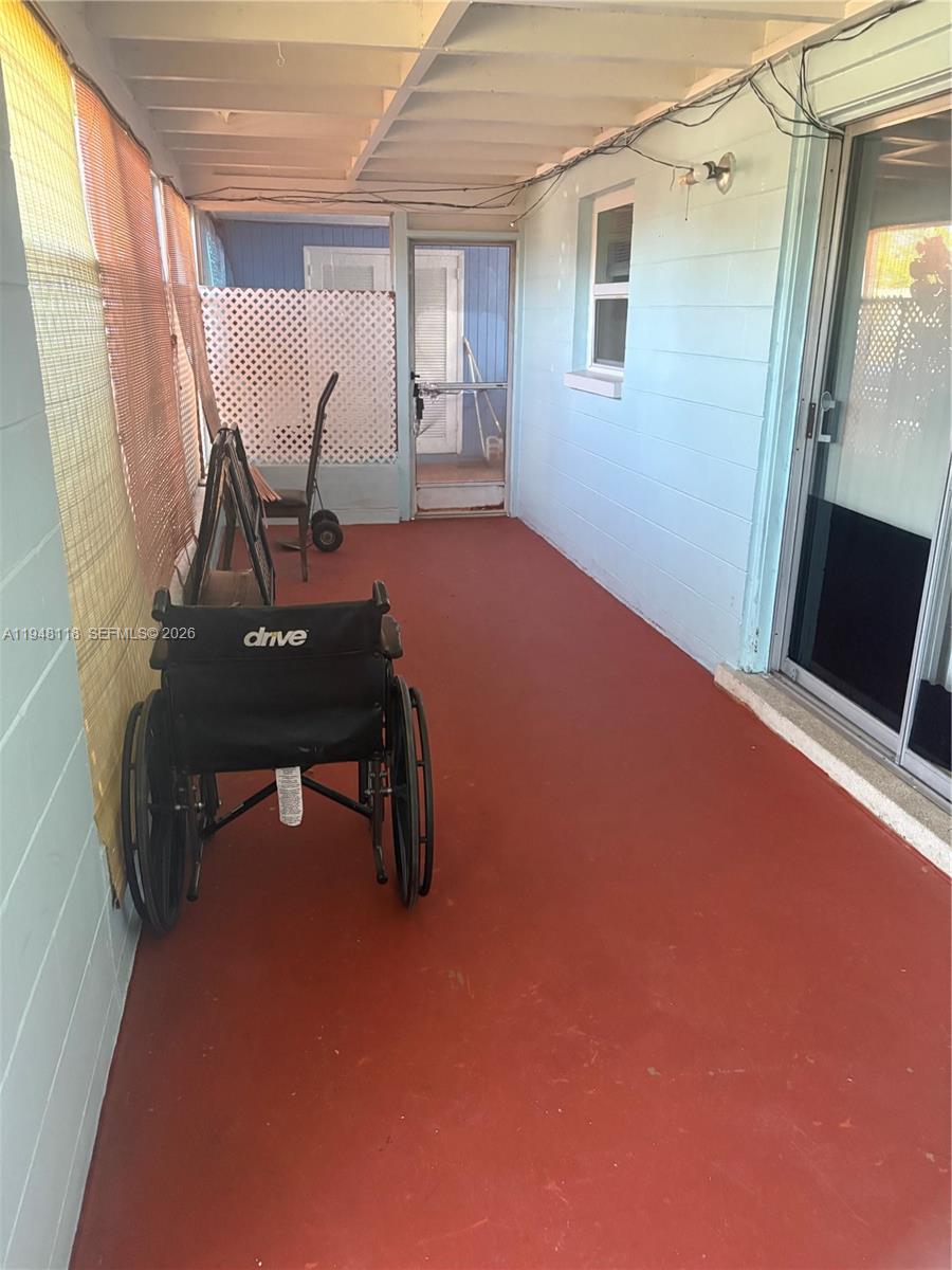A covered porch with a red floor, light blue walls, and a wheelchair — 108 Coolidge ave, Lehigh Acres FL 33936, LEHIGH ACRES, FL