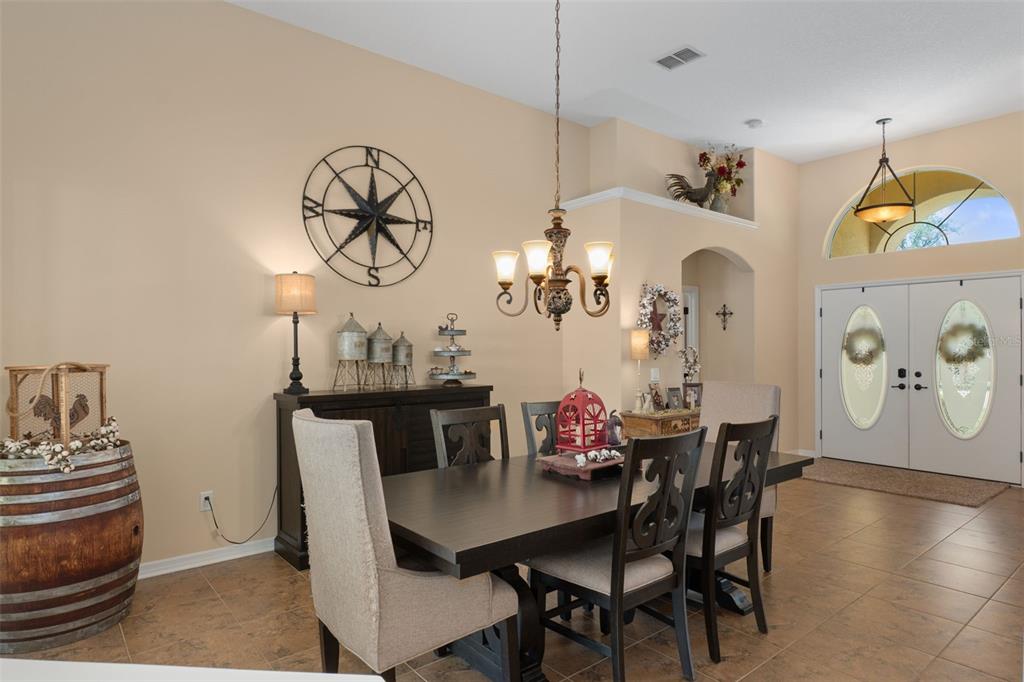 A dining room features a dark wood table, upholstered chairs, a chandelier, and a compass wall decoration — 4081 W ROUNDUP COURT, BEVERLY HILLS, FL