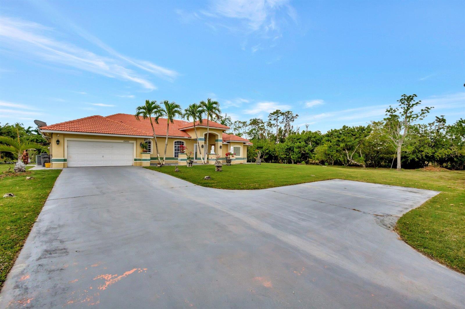 A single-story house with a tile roof, a two-car garage, and a large concrete driveway — 12402 83rd Lane N, FL 33412, FL