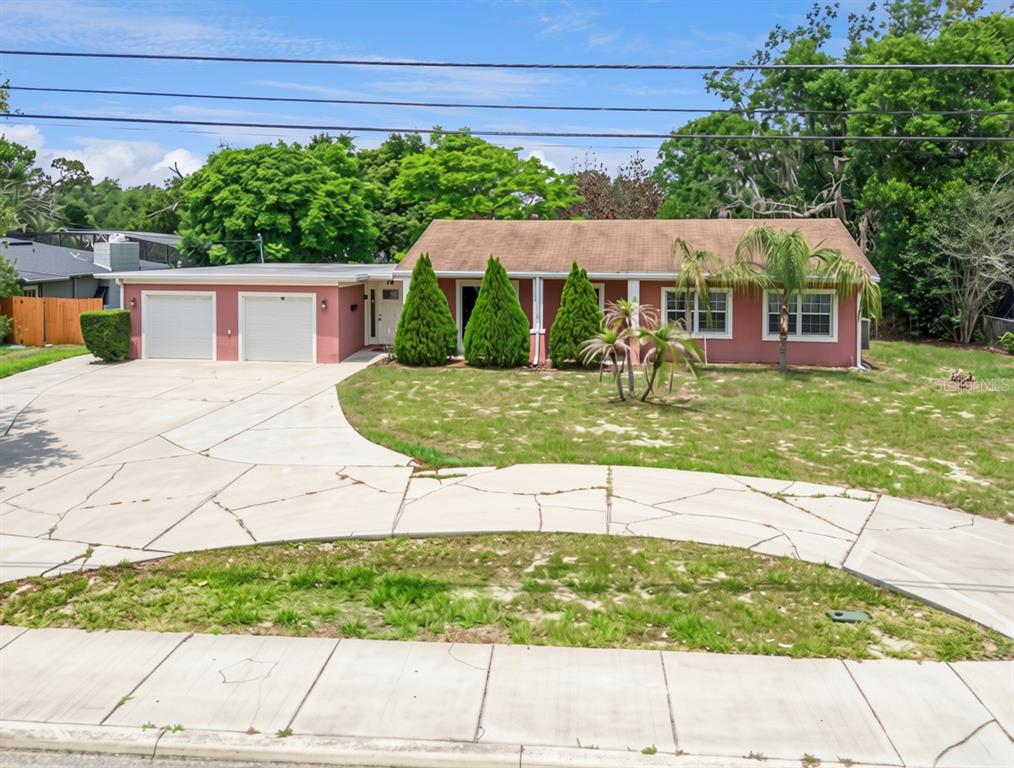 A single-story pink house with a two-car garage and a large, cracked concrete driveway — 78 S WINTER PARK DRIVE, CASSELBERRY, FL