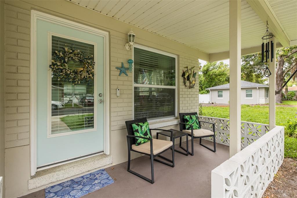 A covered front porch features a light blue door, two chairs, and a decorative breeze block wall — 5708 HOMECREST ROAD, NEW PORT RICHEY, FL