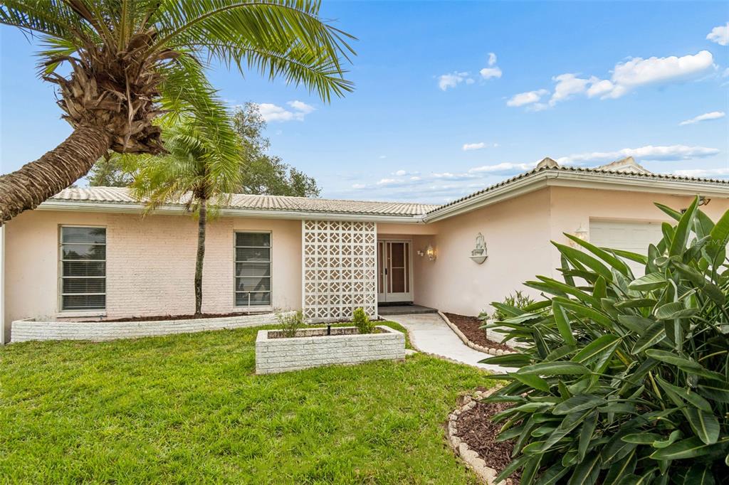 A single-story house with a light pink exterior, a palm tree, and a decorative screen wall — 14363 NEPTUNE ROAD, SEMINOLE, FL