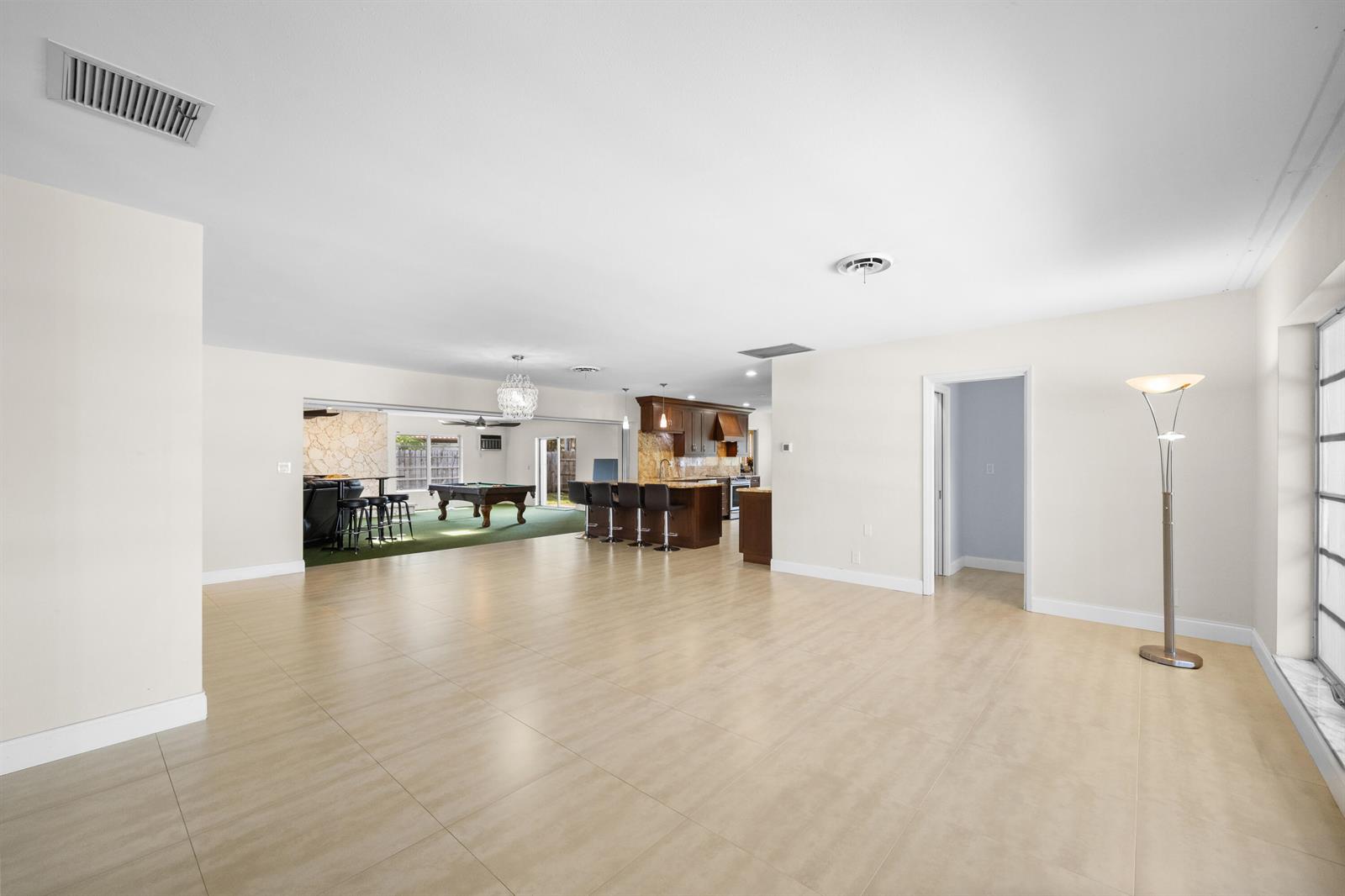 A spacious open-concept living area features large light-colored floor tiles and a kitchen island — 1500 SE 24th Avenue, Pompano Beach FL 33062, POMPANO BEACH, FL