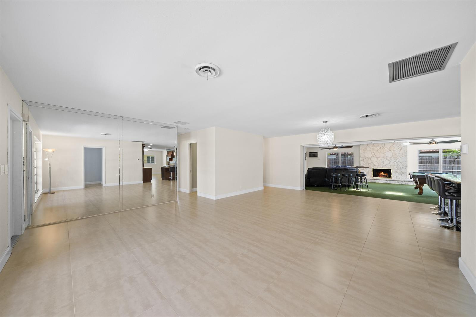 A spacious room features large floor tiles, a mirrored wall, and an open adjacent area — 1500 SE 24th Avenue, Pompano Beach FL 33062, POMPANO BEACH, FL