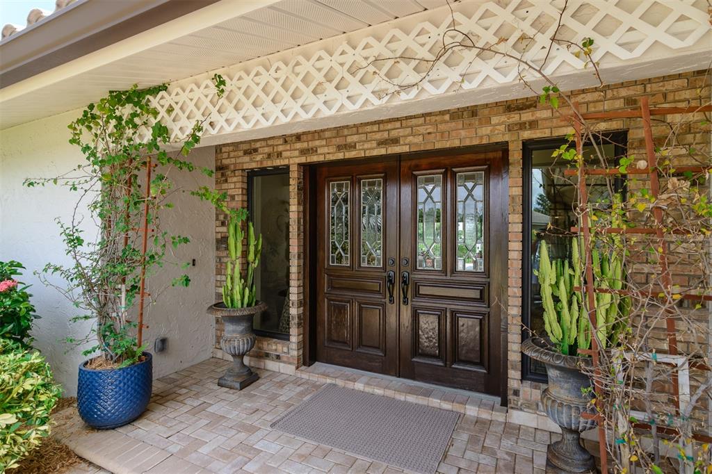 A front entryway features a double wooden door with glass panels and two potted cacti — 2860 QUAIL HOLLOW ROAD W, CLEARWATER, FL
