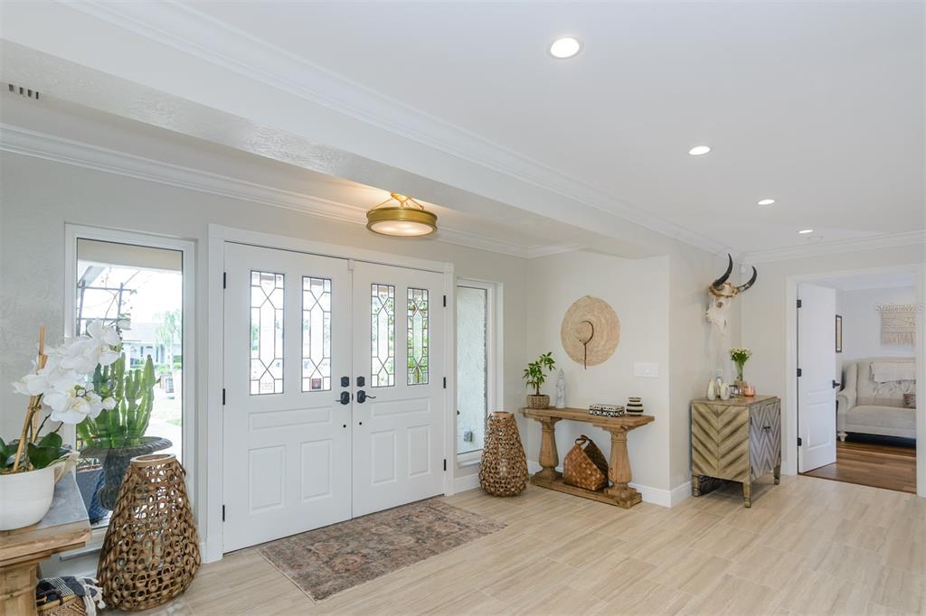 A bright entryway features double white doors, tile flooring, a wooden console table, and decor — 2860 QUAIL HOLLOW ROAD W, CLEARWATER, FL