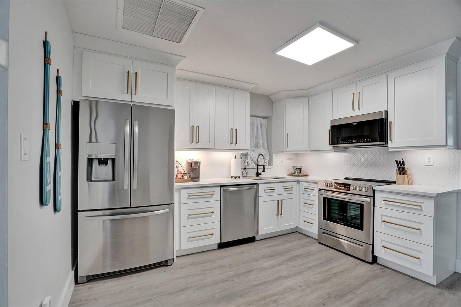 A modern kitchen features white cabinets, stainless steel appliances, gold hardware, and light wood flooring — 1969 NE 5th Street # 2, Deerfield Beach FL 33441, DEERFIELD BEACH, FL