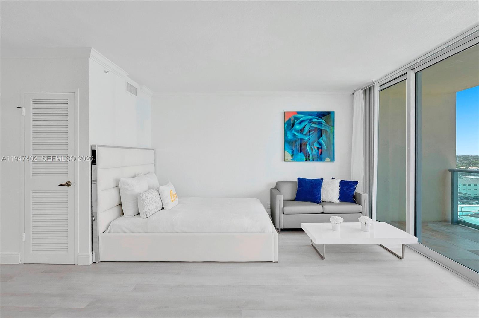 A bedroom features a white bed, a grey sofa, and a balcony with ocean views — 2501 S Ocean Dr, Hollywood FL 33019, HOLLYWOOD, FL