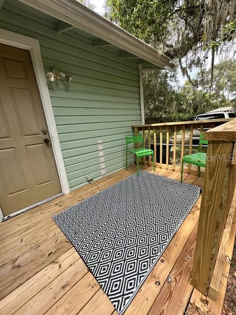 A wooden deck features a black and white geometric rug and two green chairs — 725 NE 5TH AVENUE, GAINESVILLE, FL