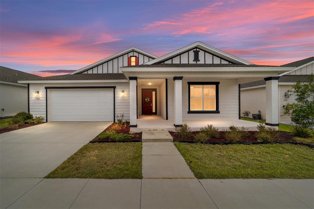 A single-story house with white siding, a two-car garage, and a covered front porch — 7513 SW 64TH STREET ROAD, OCALA, FL