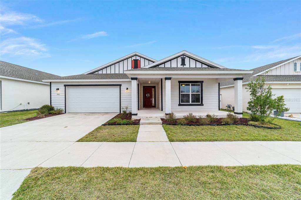 A single-story house with a white horizontal-siding exterior, a two-car garage, and a front porch — 7513 SW 64TH STREET ROAD, OCALA, FL