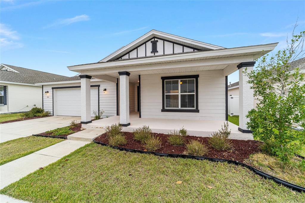 A single-story house with a white exterior, a covered front porch, and a garage — 7513 SW 64TH STREET ROAD, OCALA, FL