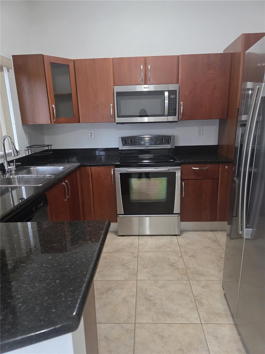 A kitchen features dark wood cabinets, black granite countertops, and stainless steel appliances — 7477 NW 181, Hialeah FL 33015, HIALEAH, FL