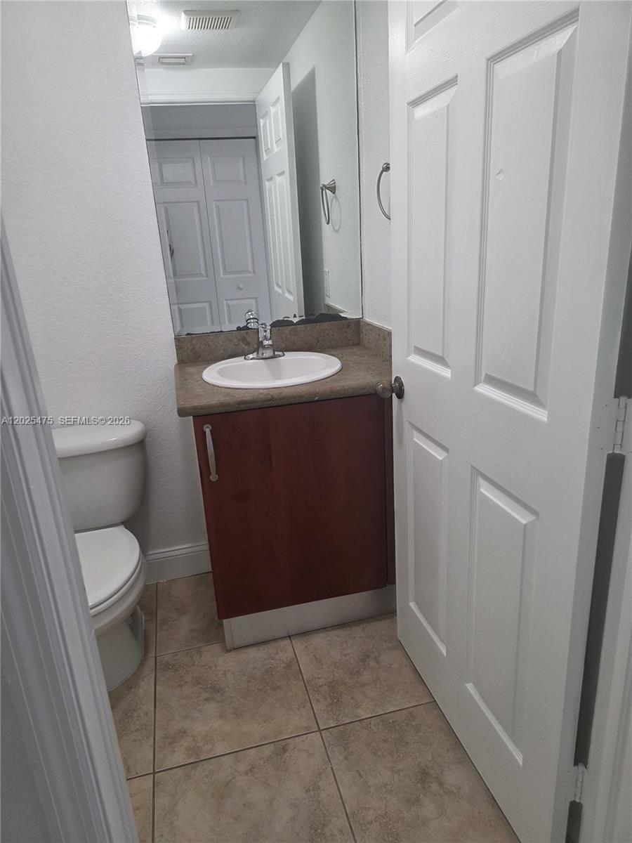 A small bathroom features a vanity with a sink, a toilet, and tile flooring — 7477 NW 181, Hialeah FL 33015, HIALEAH, FL