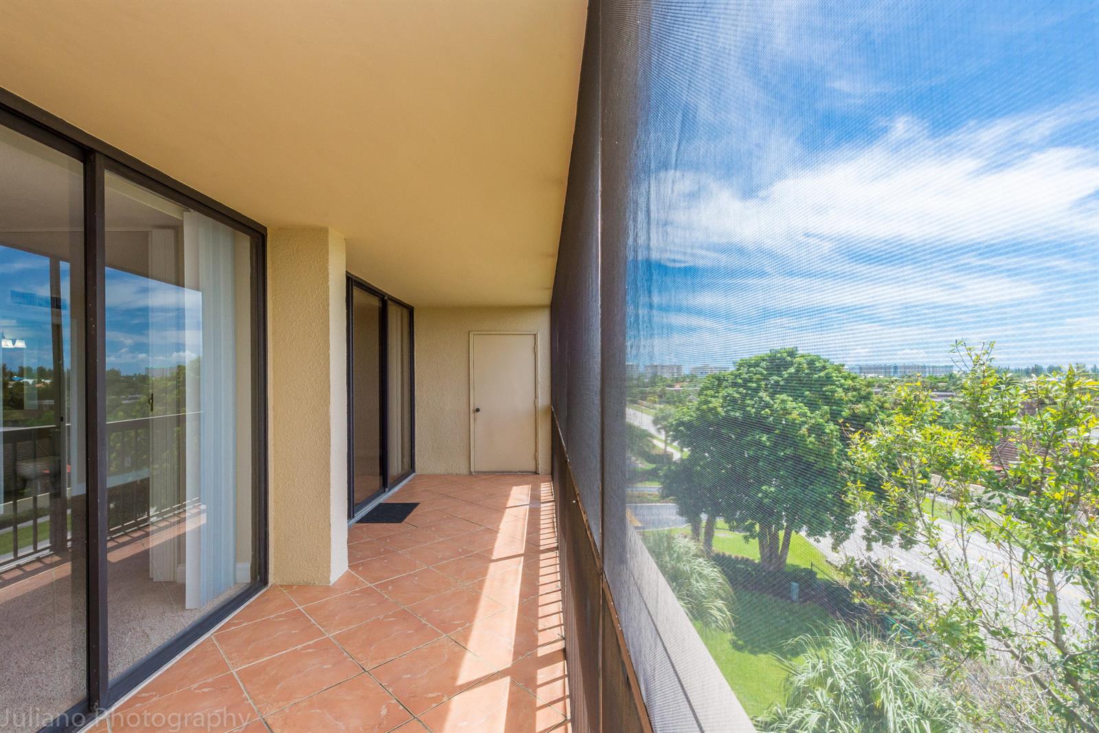 A screened-in balcony features tiled flooring, sliding glass doors, and a view of trees — 1605 S Us Highway 1 # 506, Jupiter FL 33477, JUPITER, FL