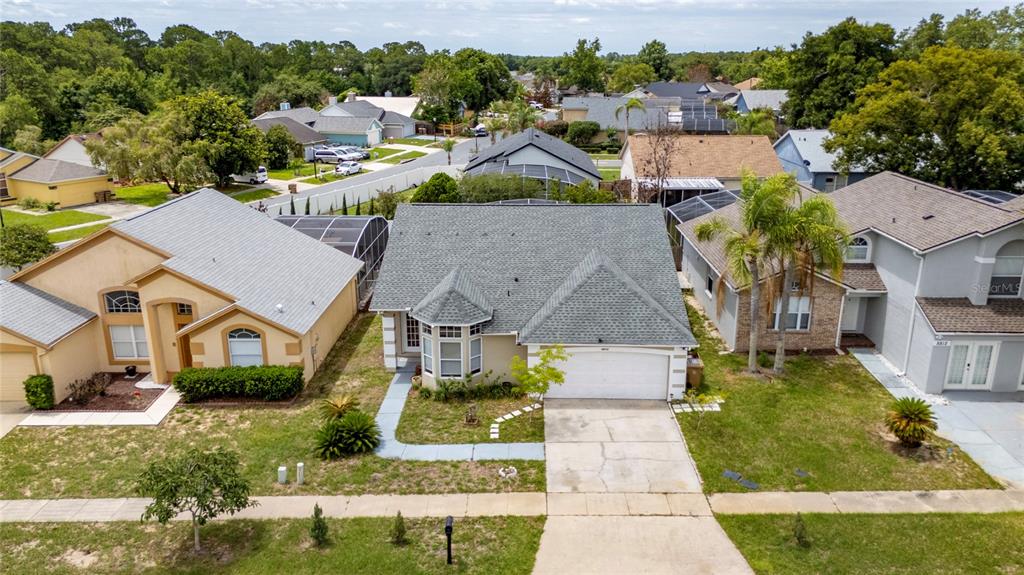 An aerial view shows a single-story suburban house with a gray roof and driveway — 8810 KENSINGTON COURT, KISSIMMEE, FL