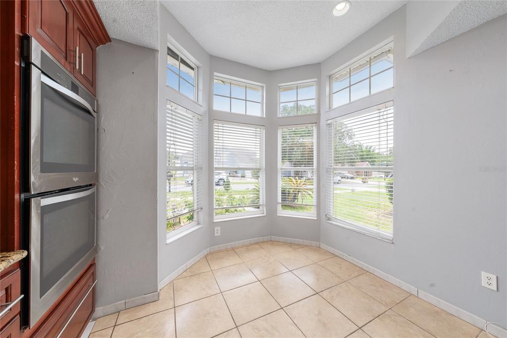A kitchen breakfast nook features tile flooring, a bay window, and a built-in double oven — 8810 KENSINGTON COURT, KISSIMMEE, FL