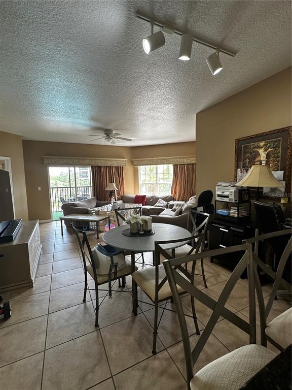 A kitchen features light-colored textured cabinets, stainless steel appliances, and tan tile flooring — 8601 WORLDQUEST BOULEVARD UNIT 3-303, ORLANDO, FL