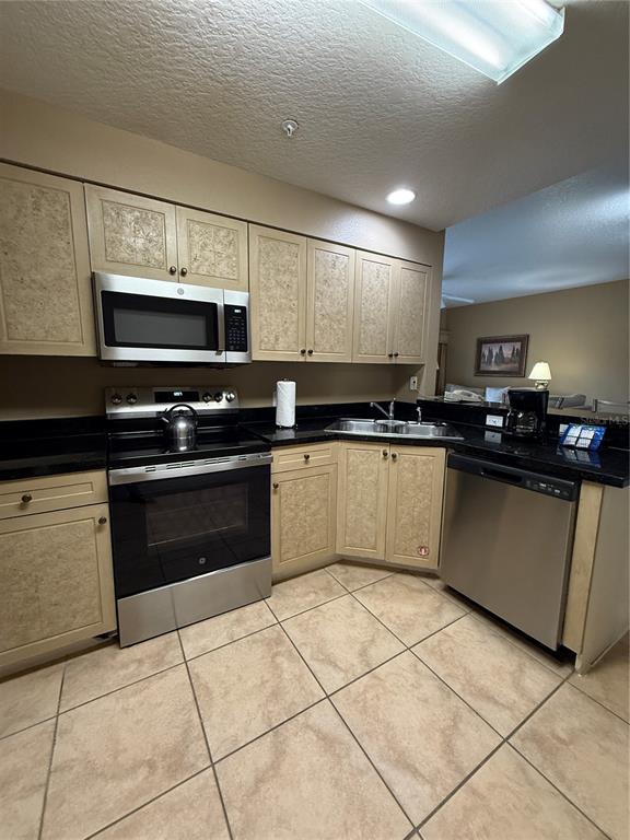 A large entertainment center with a television, shelving, and a stone-textured base cabinet — 8601 WORLDQUEST BOULEVARD UNIT 3-303, ORLANDO, FL
