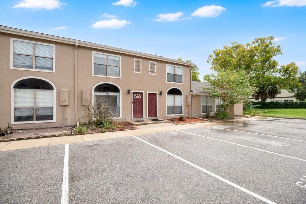 A two-story tan stucco townhouse exterior with two red front doors and a parking lot — 611 CASA PARK A COURT, WINTER SPRINGS, FL