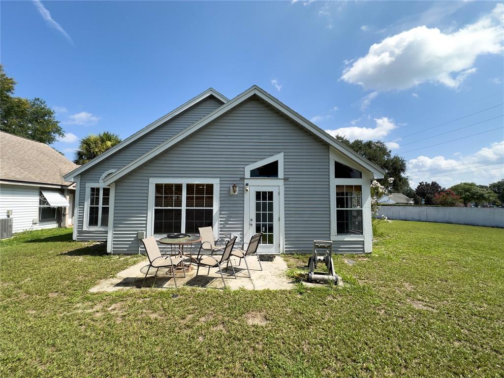 The exterior of a gray-sided house features a concrete patio with outdoor furniture — 9901 ALOMA BEND LANE, OVIEDO, FL