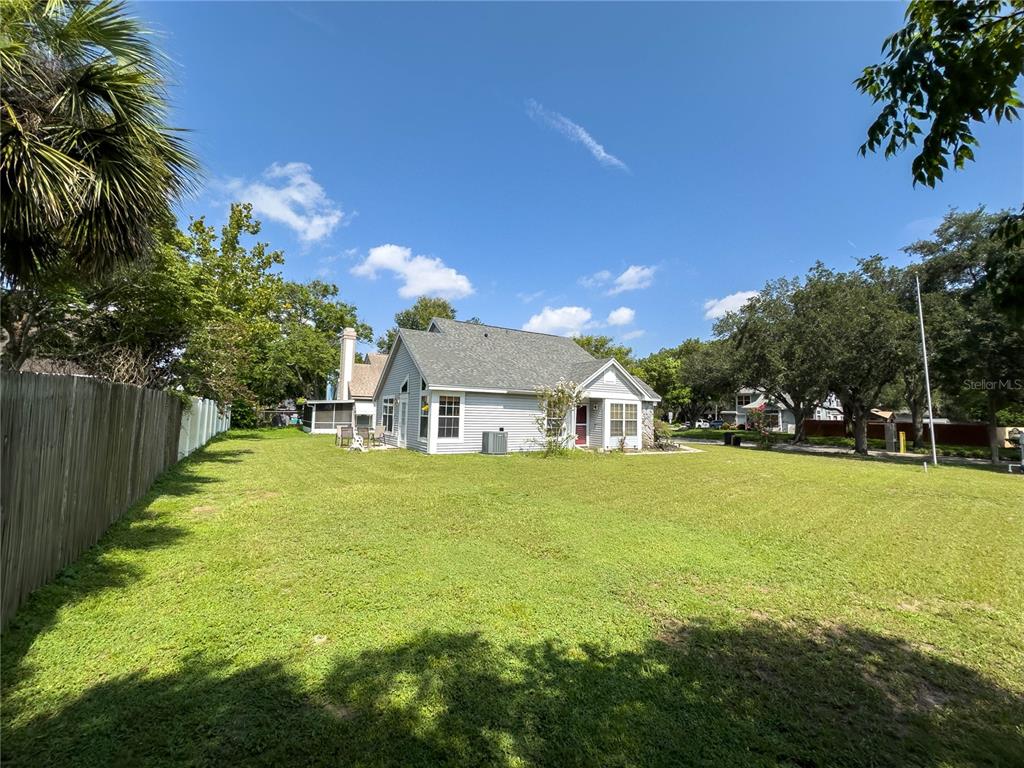 A view of a house exterior with a large grassy backyard and a wooden fence — 9901 ALOMA BEND LANE, OVIEDO, FL