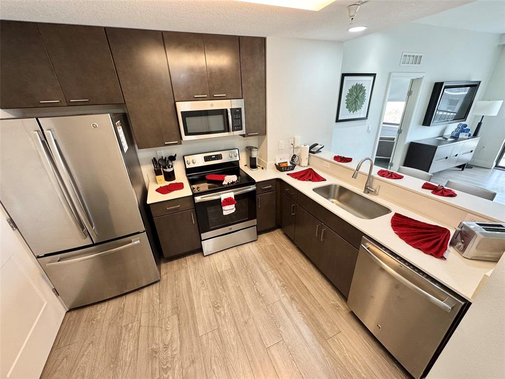 A modern kitchen features stainless steel appliances, dark wood cabinetry, and light-colored countertops — 14501 GROVE RESORT AVENUE UNIT 3630, WINTER GARDEN, FL