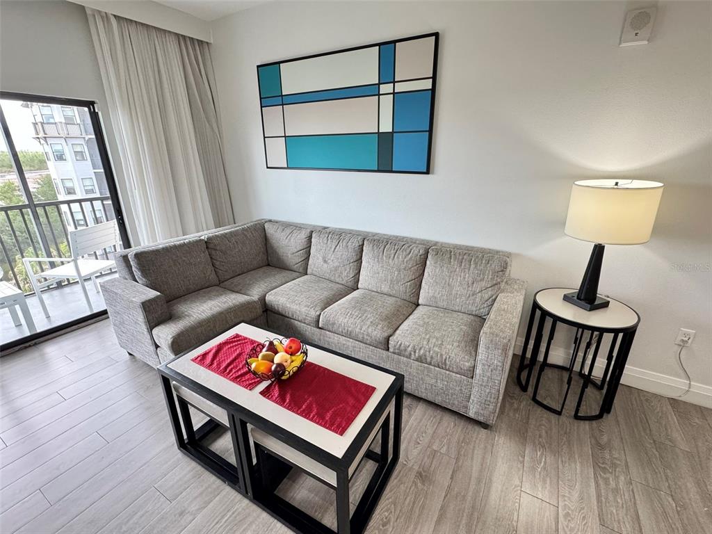 A living room features a gray sectional sofa, a coffee table, and a geometric wall painting — 14501 GROVE RESORT AVENUE UNIT 3630, WINTER GARDEN, FL
