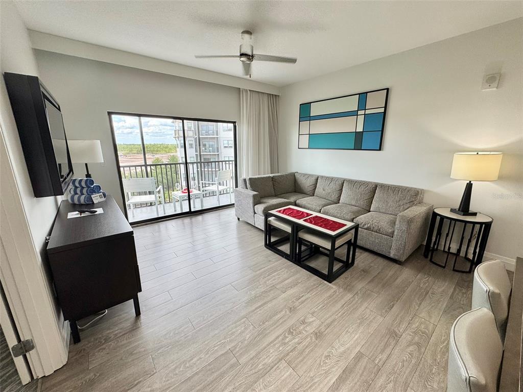 A living room features a gray sectional sofa, a coffee table, and a balcony view — 14501 GROVE RESORT AVENUE UNIT 3630, WINTER GARDEN, FL