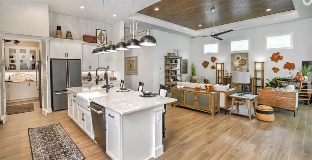 A modern open-concept kitchen and living area with white cabinetry, wood flooring, and pendant lighting — 54 BROADWATER ROAD, ORMOND BEACH, FL