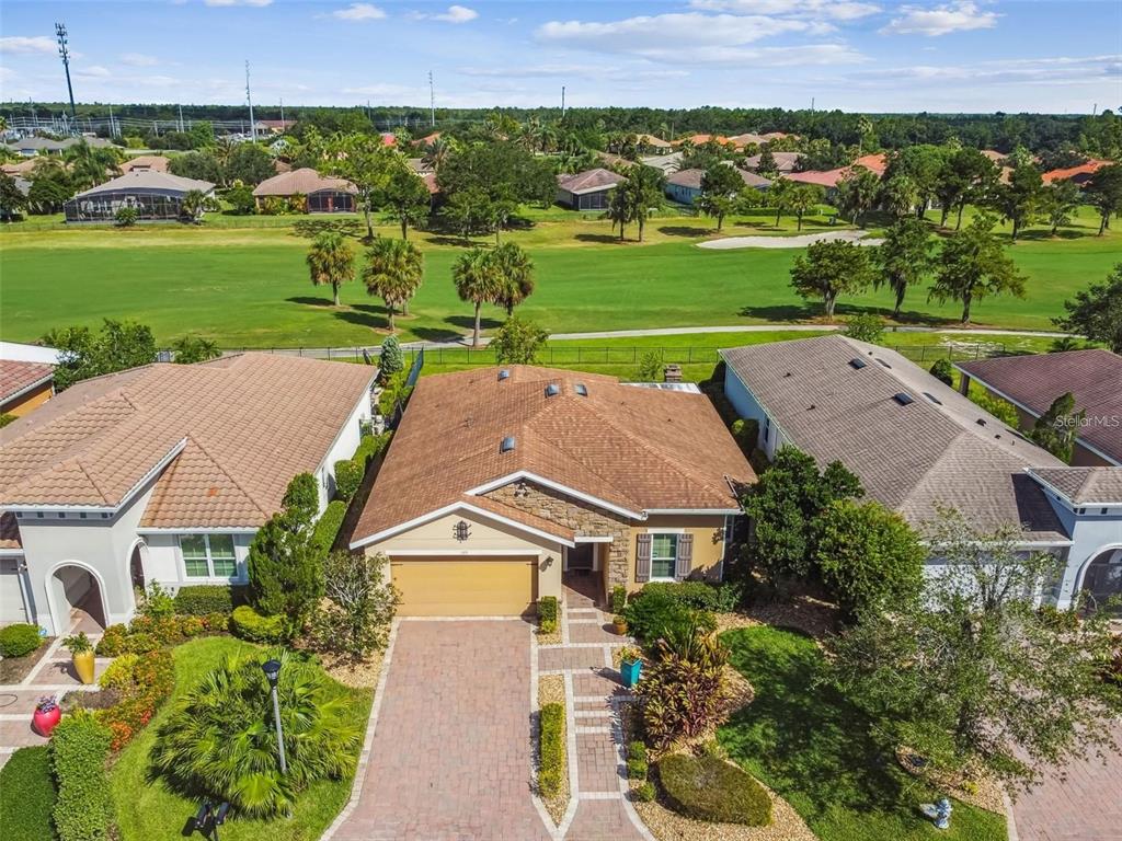 An aerial view shows a single-story house with a tan roof overlooking a golf course — 159 CASAVISTA DRIVE, KISSIMMEE, FL