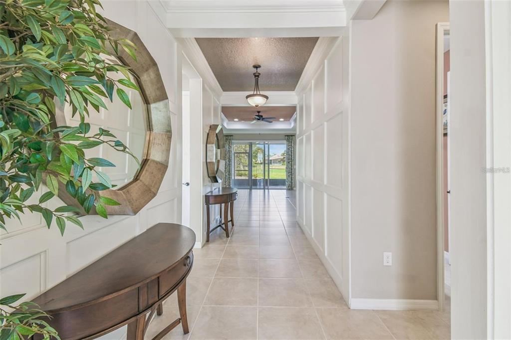 A bright hallway features white paneled walls, tile flooring, and a view toward a patio — 159 CASAVISTA DRIVE, KISSIMMEE, FL