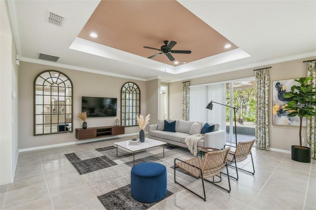 A living room with a tray ceiling, arched mirrors, a gray sofa, and tile flooring — 159 CASAVISTA DRIVE, KISSIMMEE, FL