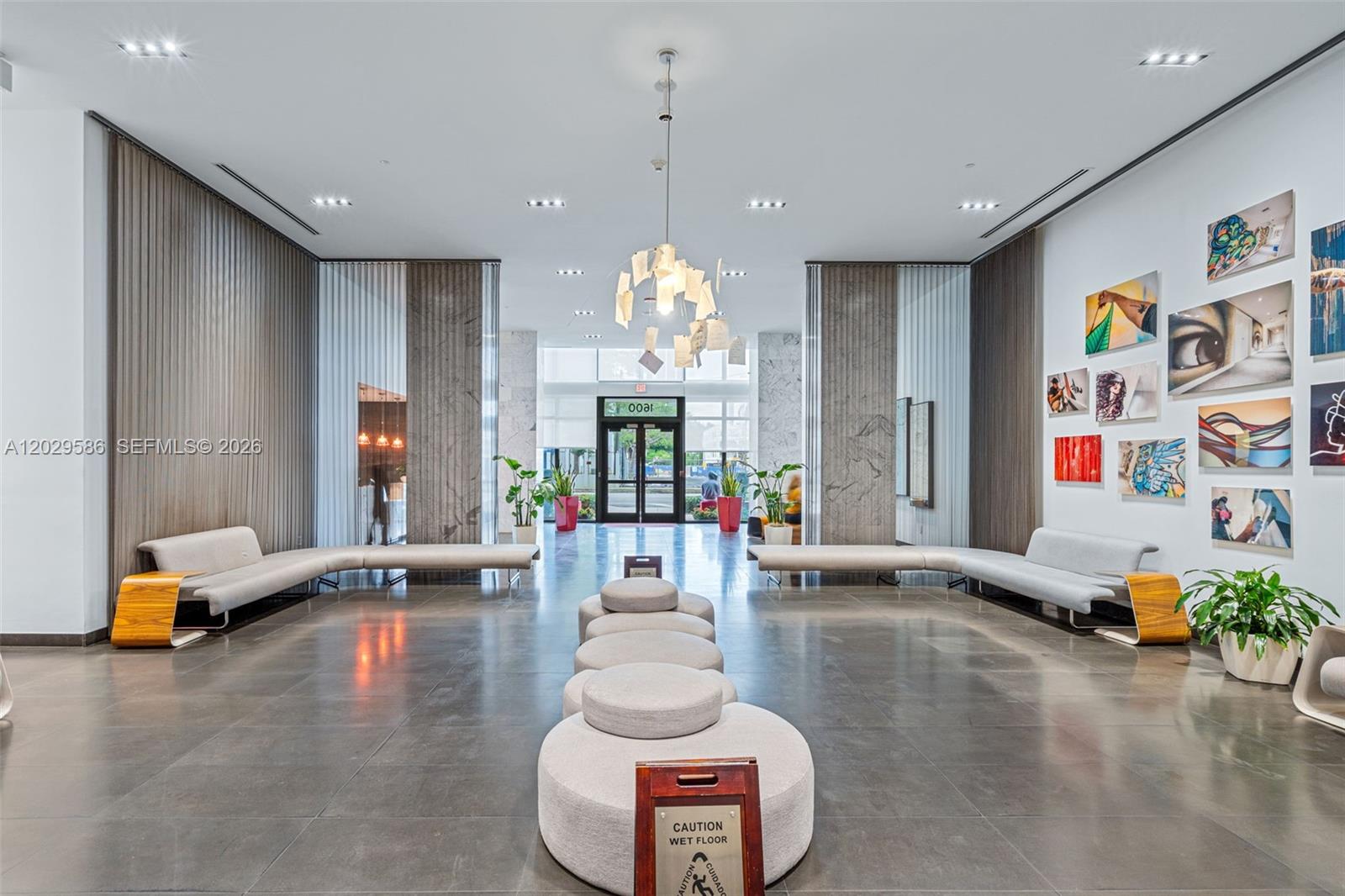 A modern building lobby features gray tiled floors, modular seating, and a decorative paper chandelier — 1600 NE 1st Ave # 2617, Miami FL 33132, MIAMI, FL