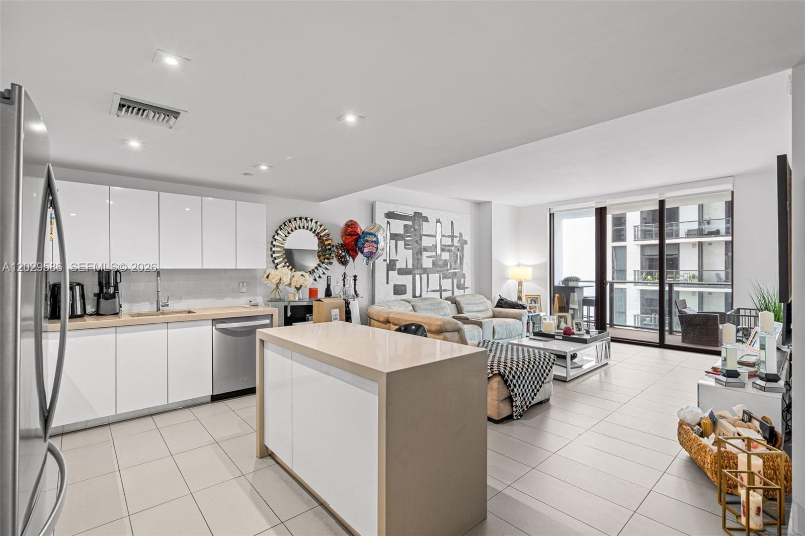 A modern open-concept kitchen and living area features white cabinetry, tile flooring, and a balcony — 1600 NE 1st Ave # 2617, Miami FL 33132, MIAMI, FL