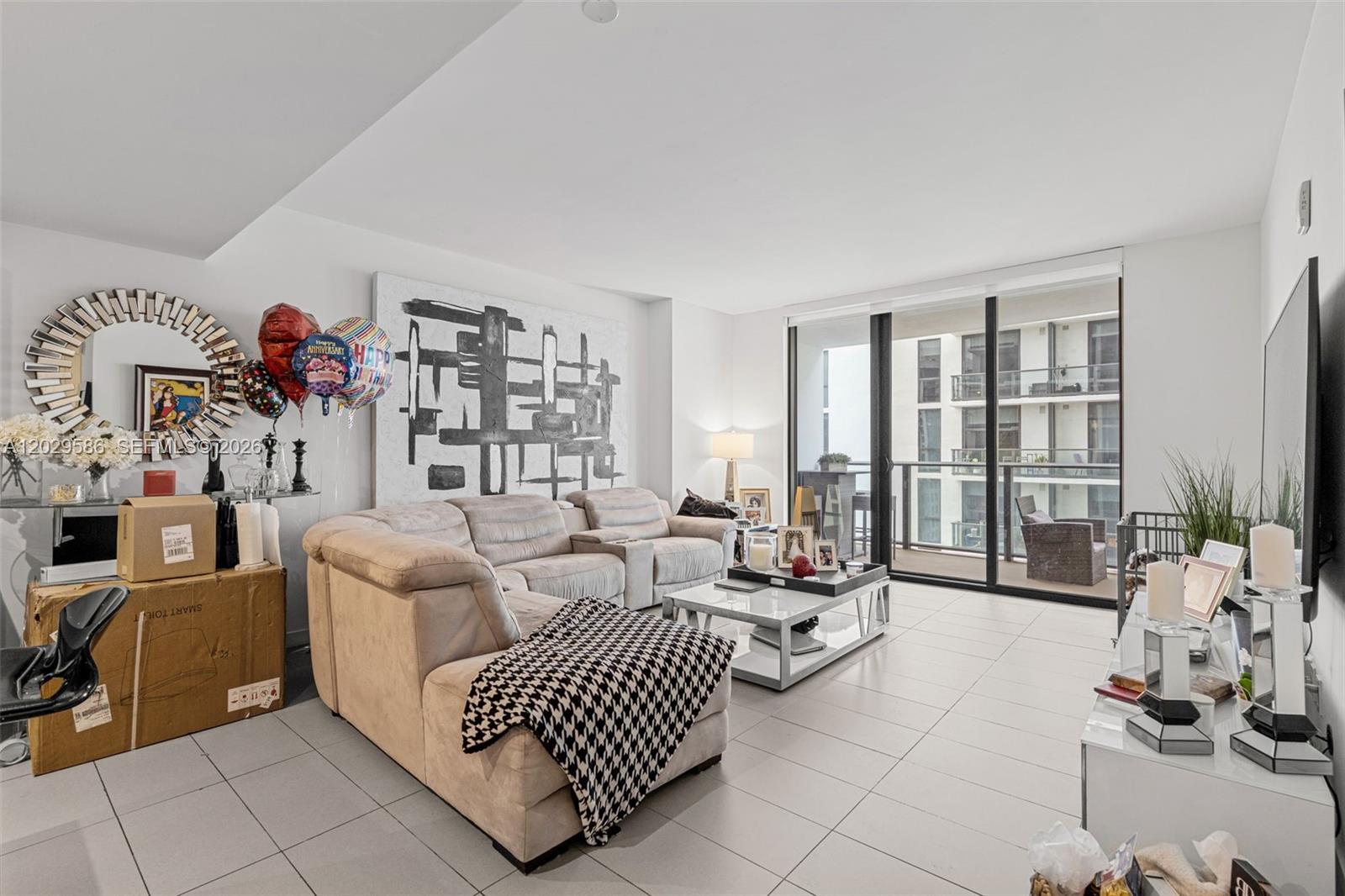 A living room features a beige sectional sofa, a glass coffee table, and a balcony view — 1600 NE 1st Ave # 2617, Miami FL 33132, MIAMI, FL