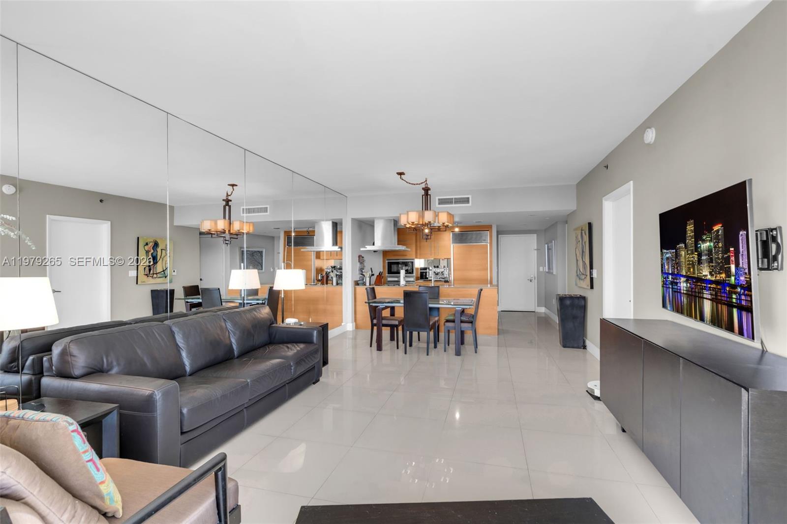 A living and dining area features a black leather sofa, tiled floors, and mirrored walls — 495 Brickell Ave # 2909, Miami FL 33131, MIAMI, FL