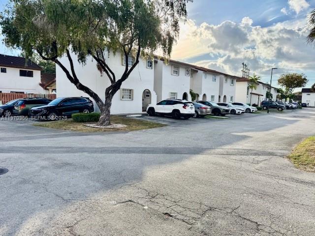A row of white townhouses sits behind a parking lot with several parked cars — 13539 SW 62nd St # 128, Miami FL 33183, MIAMI, FL