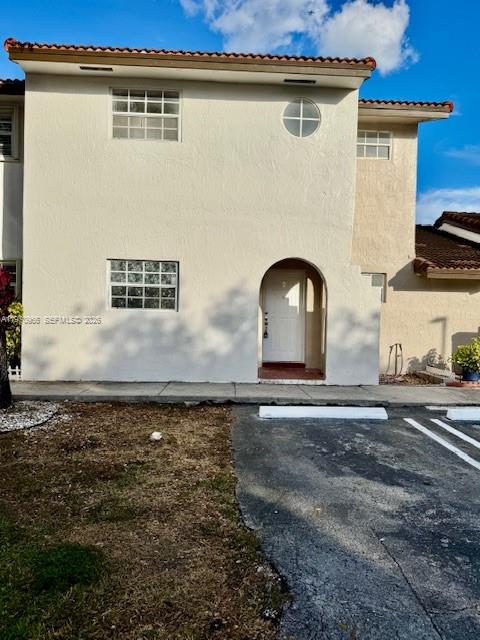 A two-story beige stucco townhouse features a recessed arched entryway and a small circular window — 13539 SW 62nd St # 128, Miami FL 33183, MIAMI, FL
