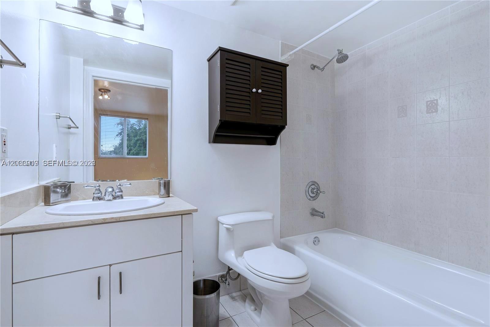 A bathroom features a white vanity, a toilet, and a shower-tub combination with tiled walls — 8888 Collins Ave # 314, Surfside FL 33154, SURFSIDE, FL