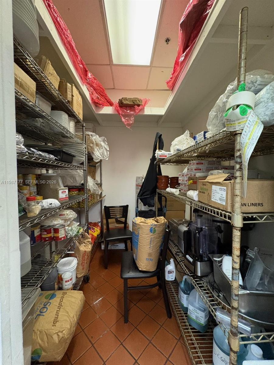 A narrow storage room features metal shelving units filled with various food supplies and equipment — Main Road, Weston FL 33327, WESTON, FL