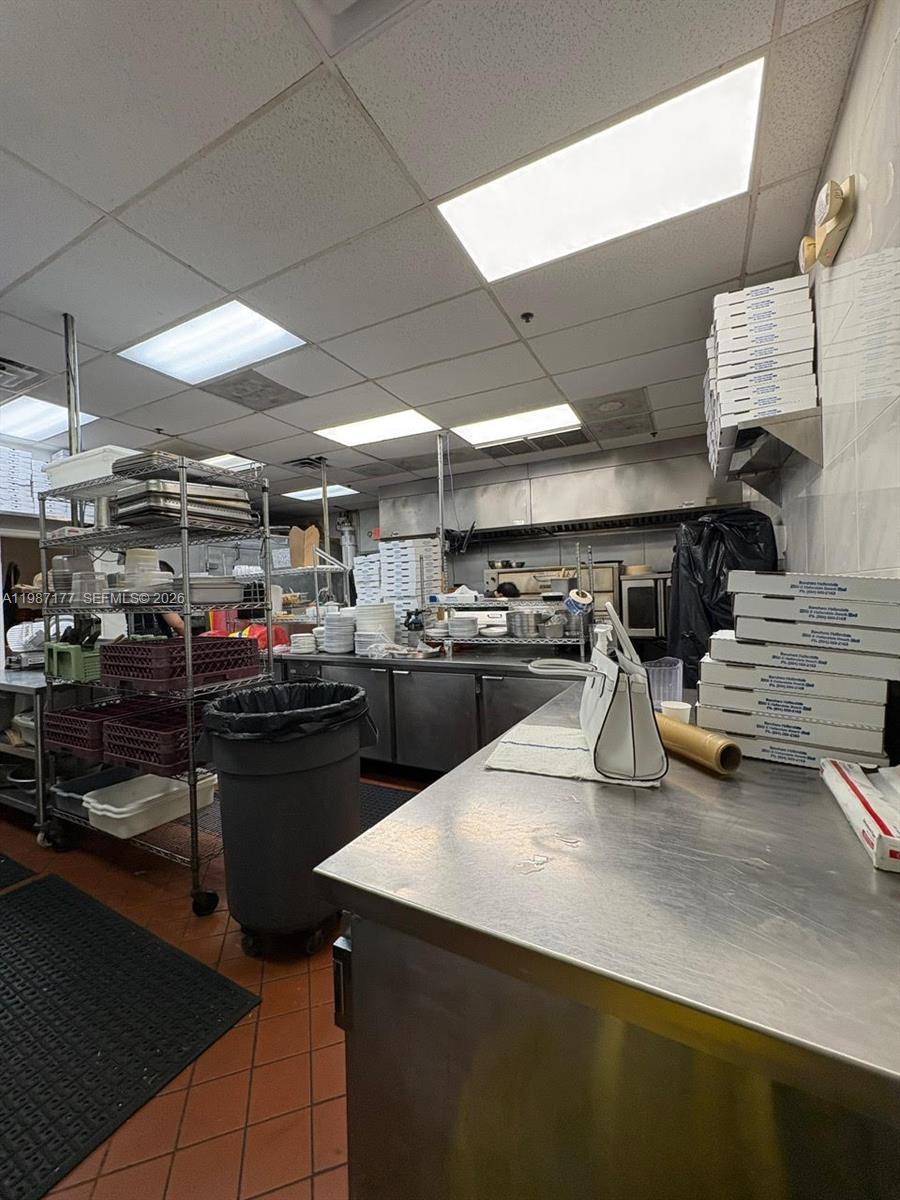 A commercial kitchen features stainless steel prep tables, stacked pizza boxes, and metal shelving units — Main Road, Weston FL 33327, WESTON, FL